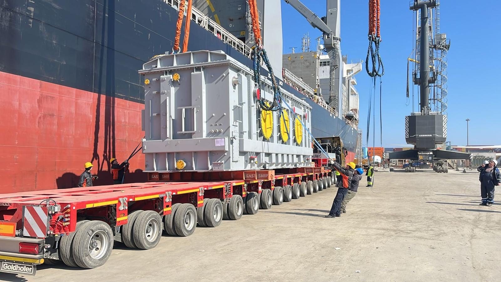 A transformer on a modular trailer alongside a heavy-lift vessel